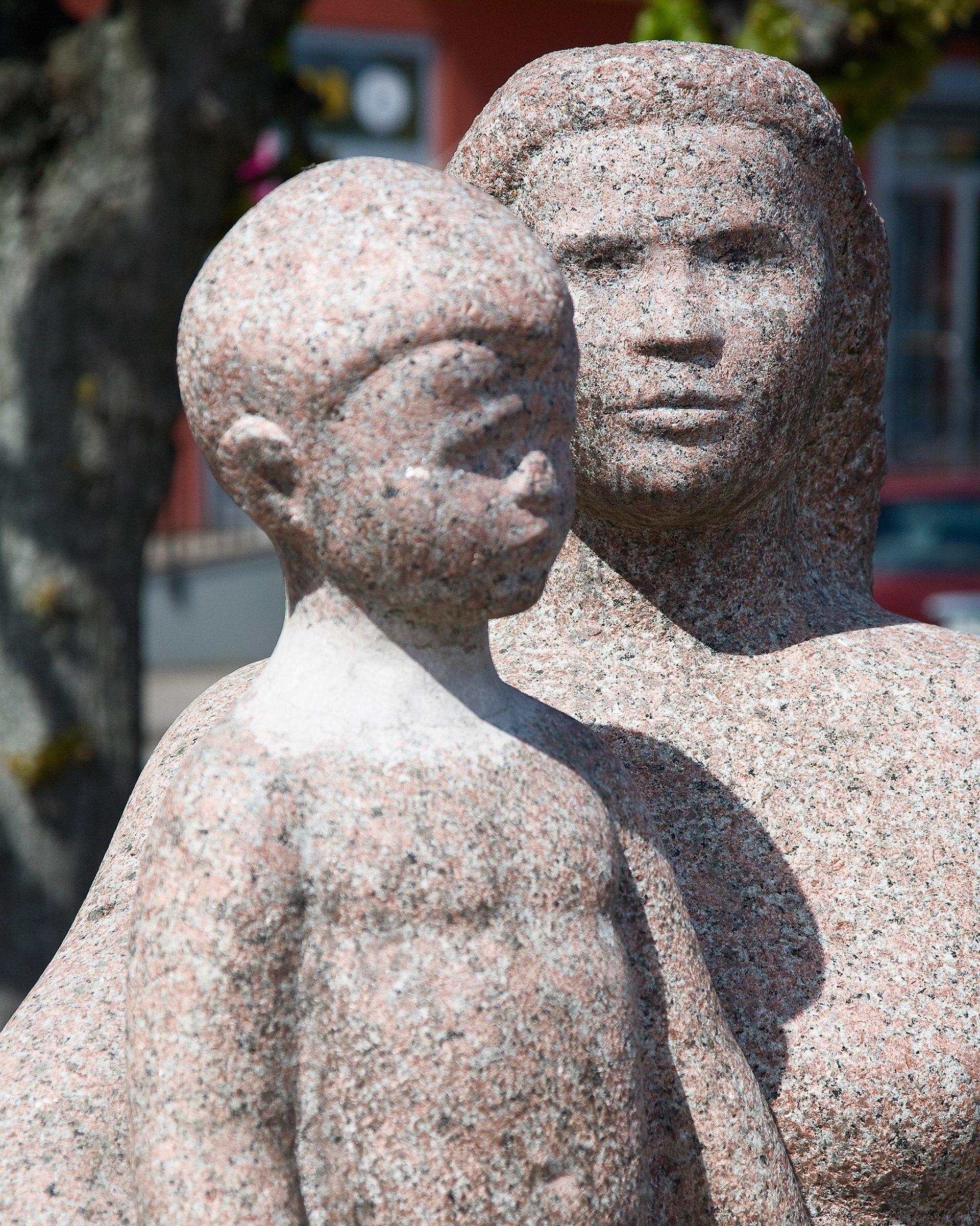 En skulptur gjord i sten pojke, bakom honom en kvinna.