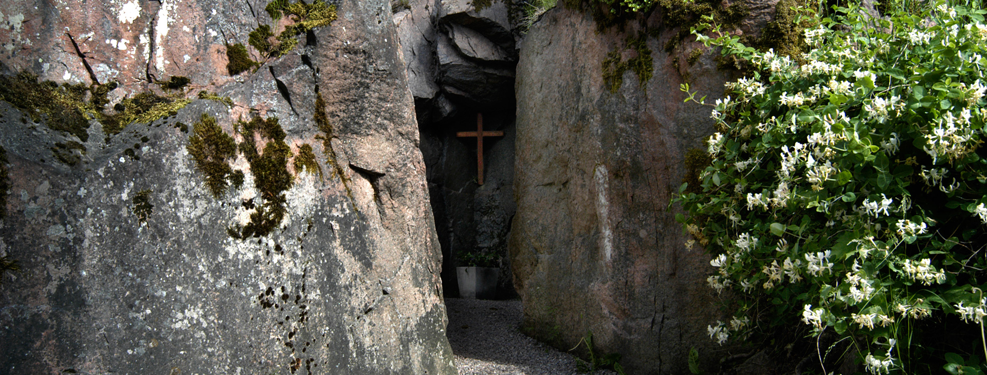 Mellan två klippor är det en smal gång in. Längs in finns ett kors uppsatt.