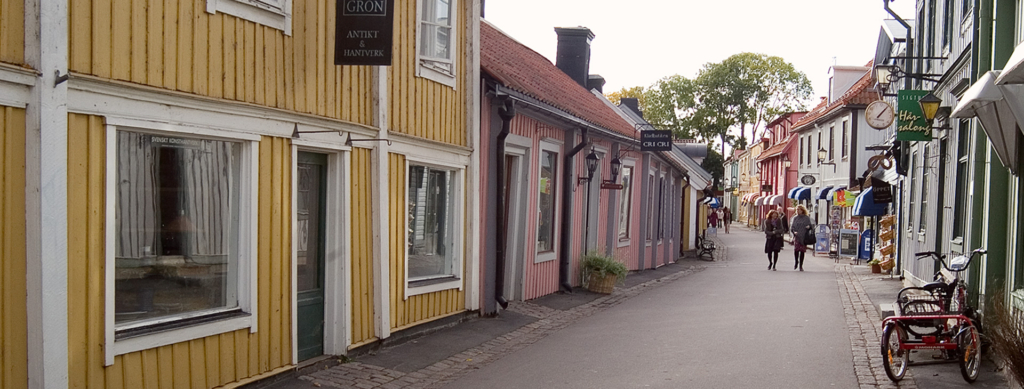 En smal gata med små hus på sidorna. Det går ett par kvinnor på gatan.