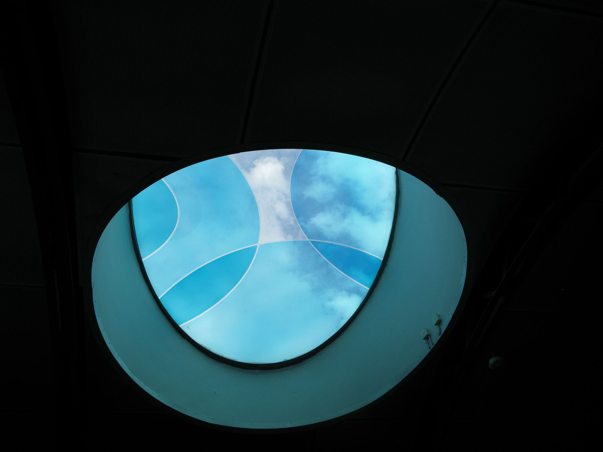 Ett blått halvrunt fönster med olika mönster och med en svart bakgrund.
