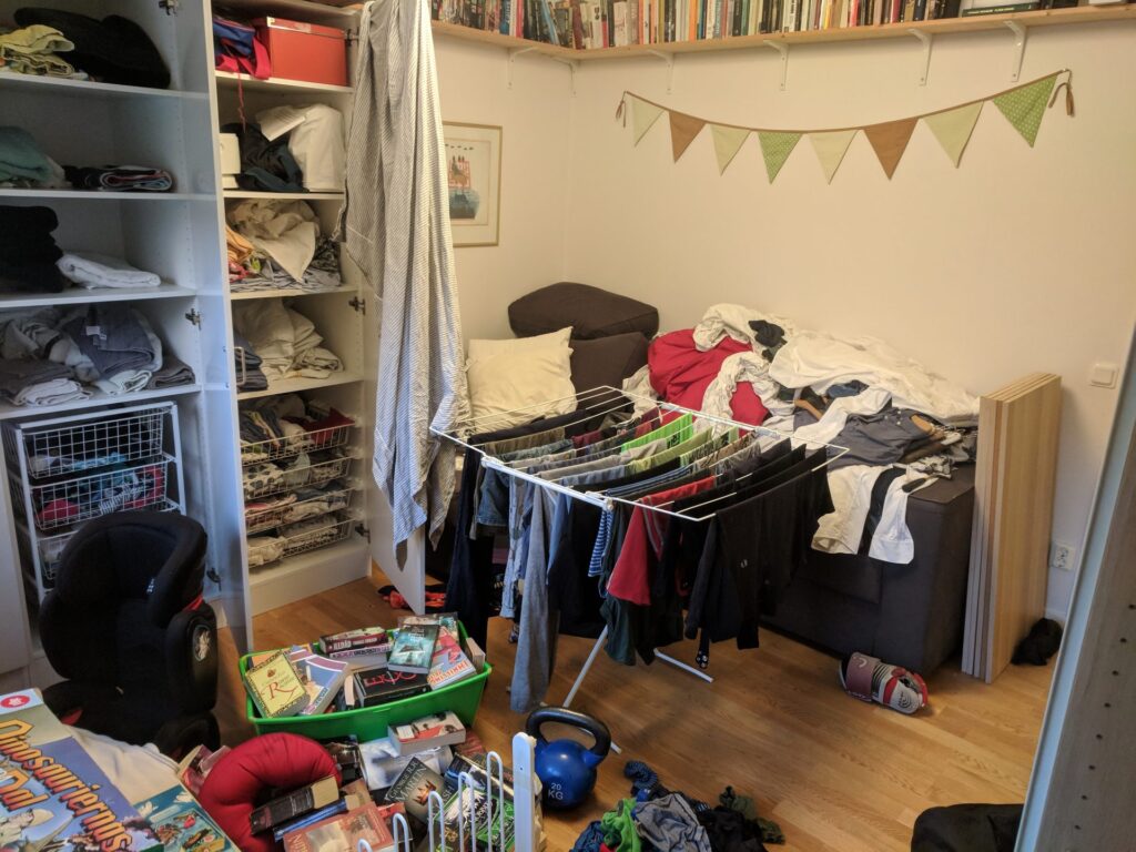 Ett rum fullt med kläder överallt. På tvättlinor, på sängen, i garderoben, på golvet.