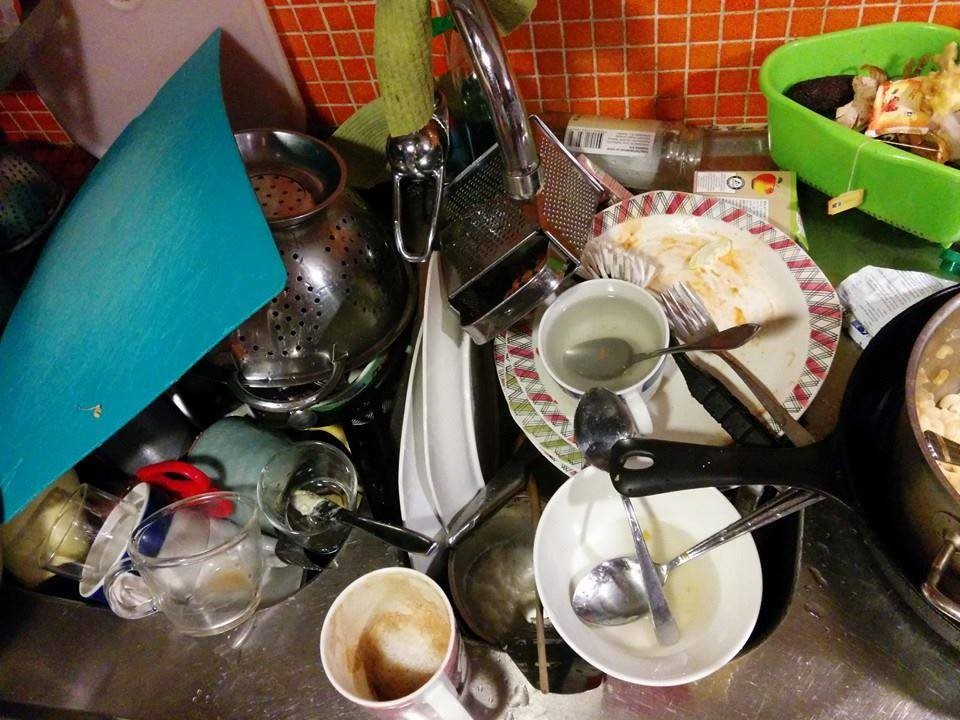 En diskbänk full med smutsiga tallrikar, glas, bestick.