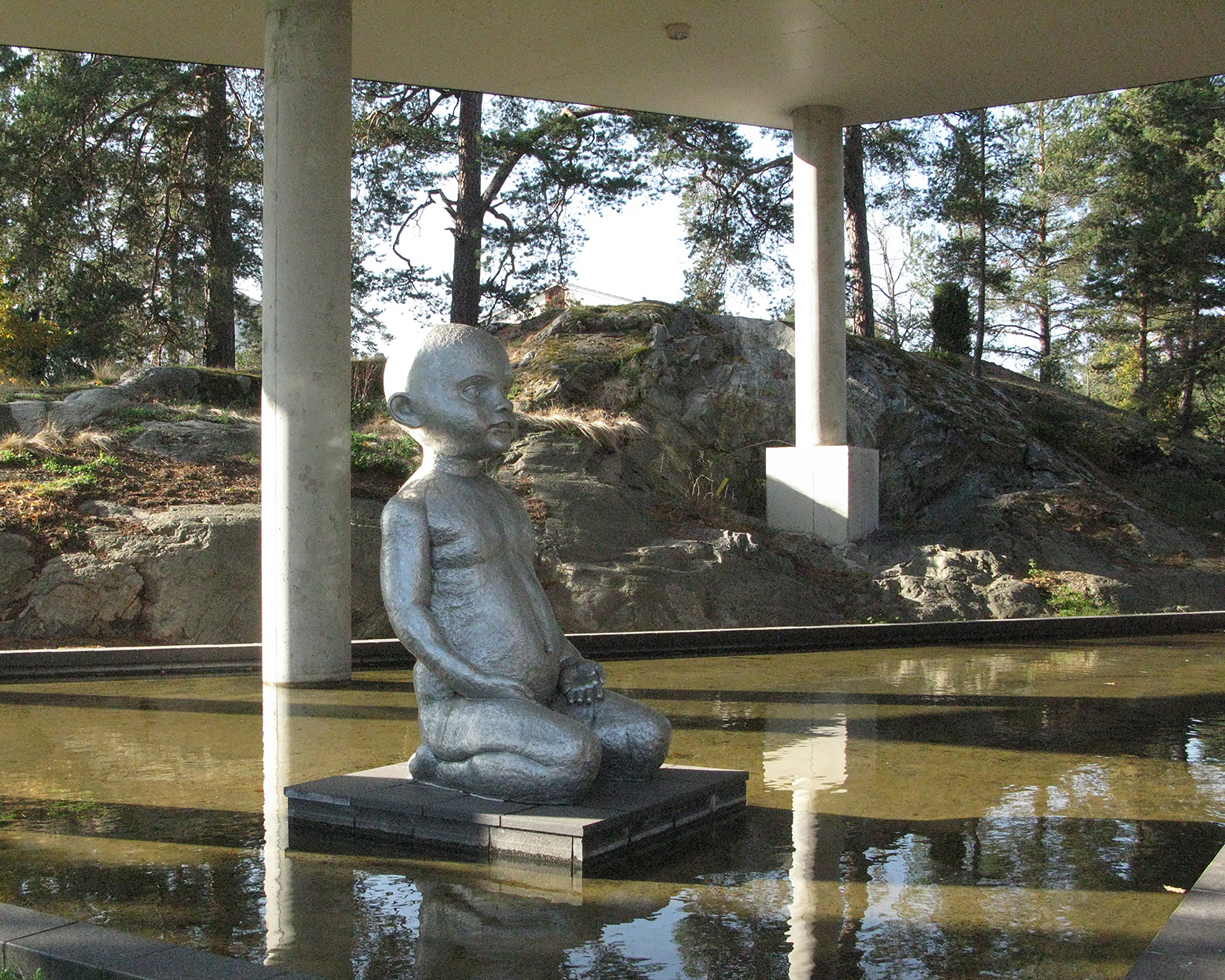En flicka gjord av sten sitter i en fontän.