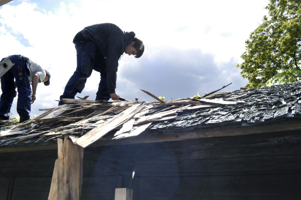 Två män står på ett tak och renoverar det.