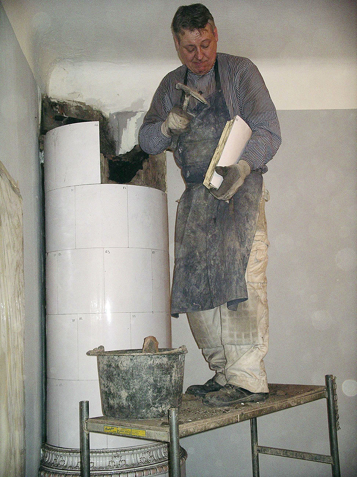 En man håller på att renovera en kakelugn.