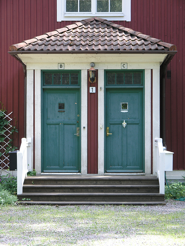 En veranda med två dörrar, en trappa leder upp till dörrarna.