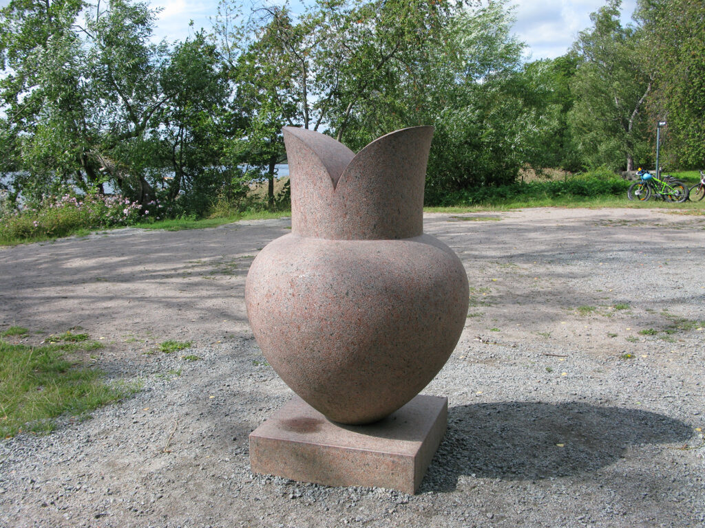 En skulptur av sten som är rund i formen men smal nertill och två böjda former upptill.