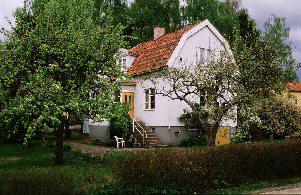 Ett hus som står bakom träd i en trädgård