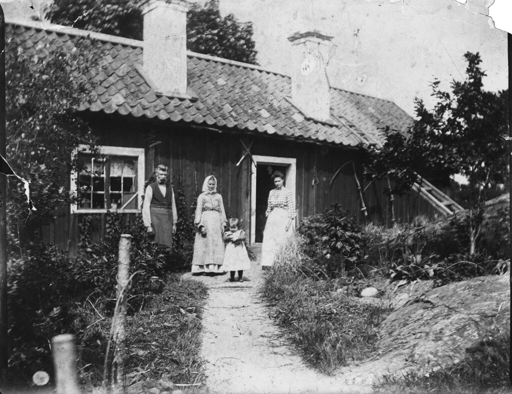 Fyra personer står framför en liten stuga.