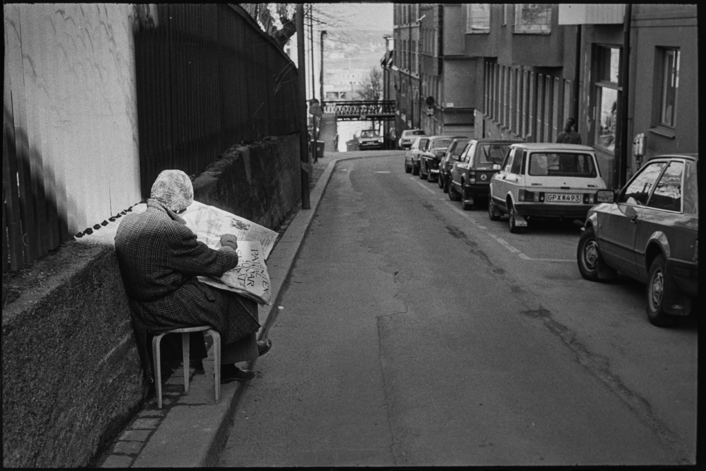 En man i pälsmössa läser tidning på Bastugatan.