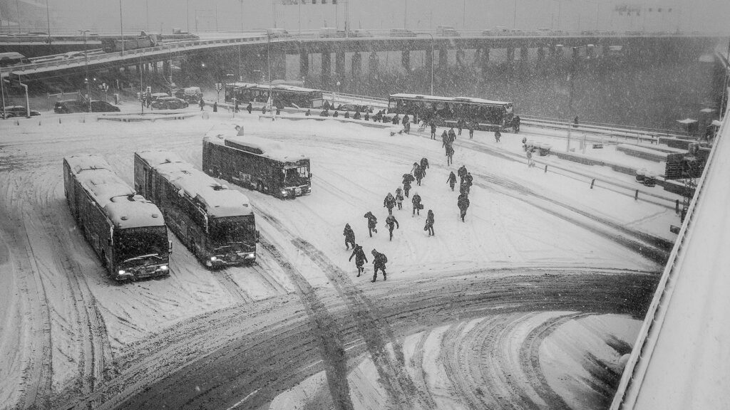Personer som går till bussar i snöstorm