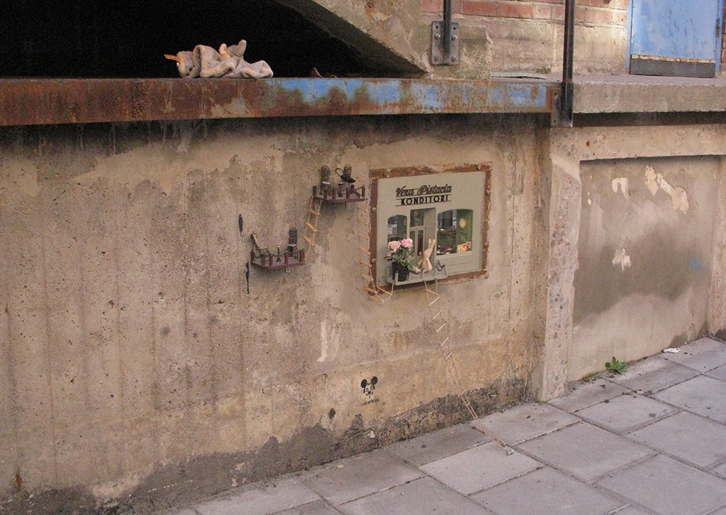 Ett tittskåp med texten Konditori på en betongvägg.  
