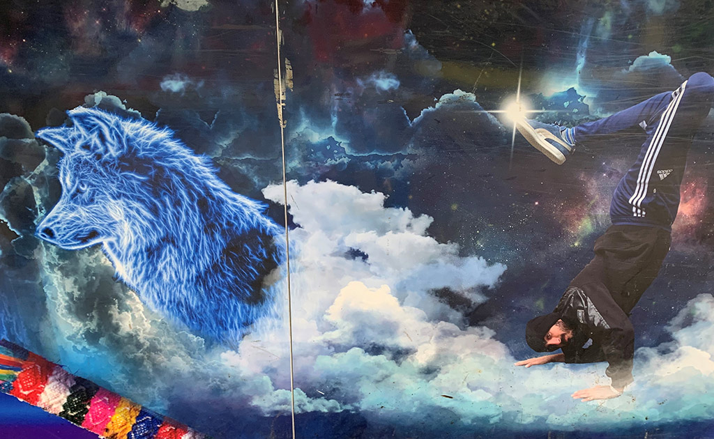Väggmålning med varg, hiphopdansare och moln.