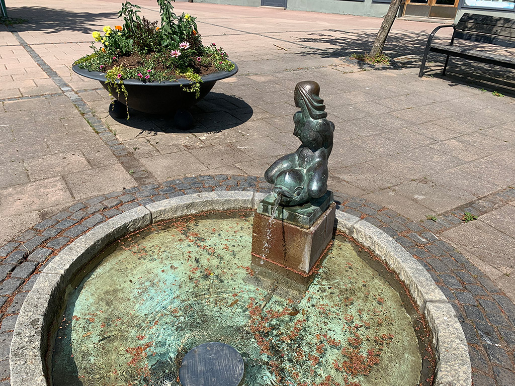 Flicka och delfin av brons i fontän.