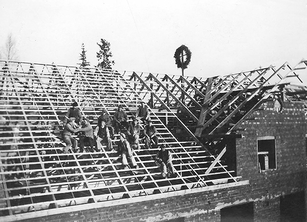 En grupp män sitter på ett tak en krans syns på en stolpe.