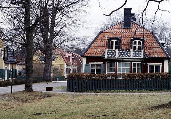 Ett hus med ett stort tak, huset står bakom ett staket.