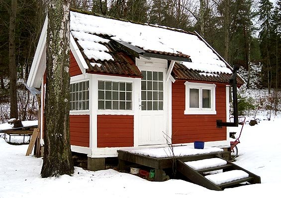 En litet hus som står i ett vinterlandskap.