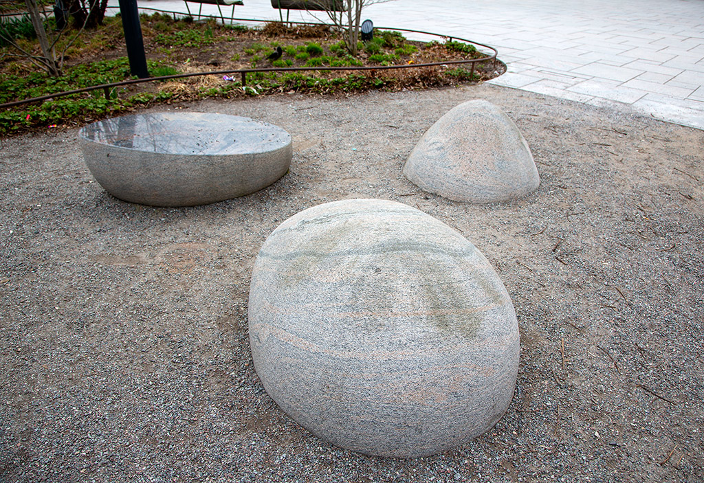 Tre slipade stenar på grus. En sten är delad och har glansig yta.