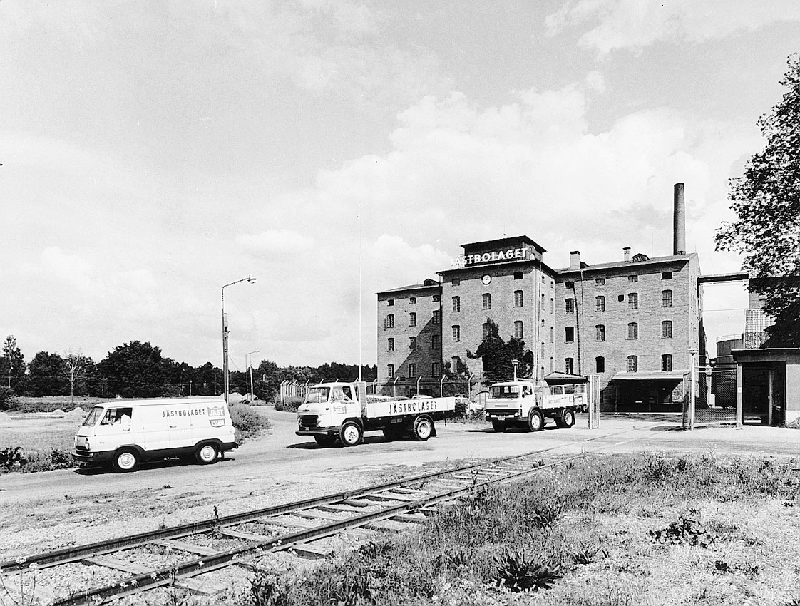 Svartvit bild som visar några bilar utanför Jästbolagets äldre fabriksbyggnad. Bilden är från 1960-talet.