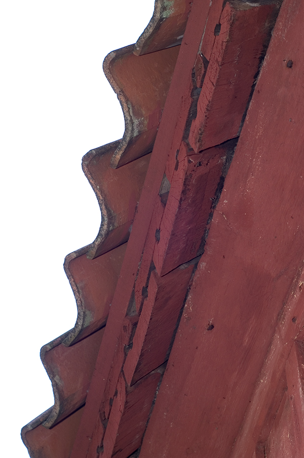 Taket fotat underifrån på ett falurött hus. Takpannorna ser ut som vågor.