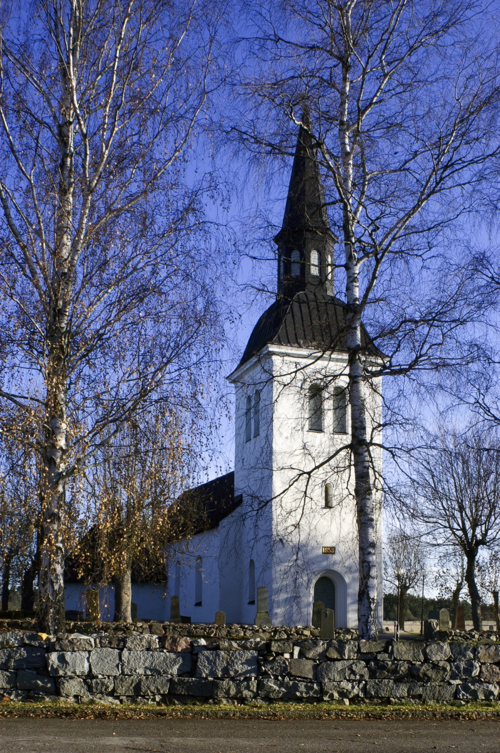 Bild på Skå kyrka, en stenkyrka med vit puts