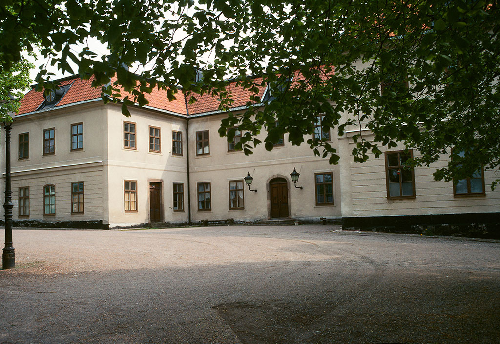 Edsbergs slott med några grenar från ett träd i förgrunden.