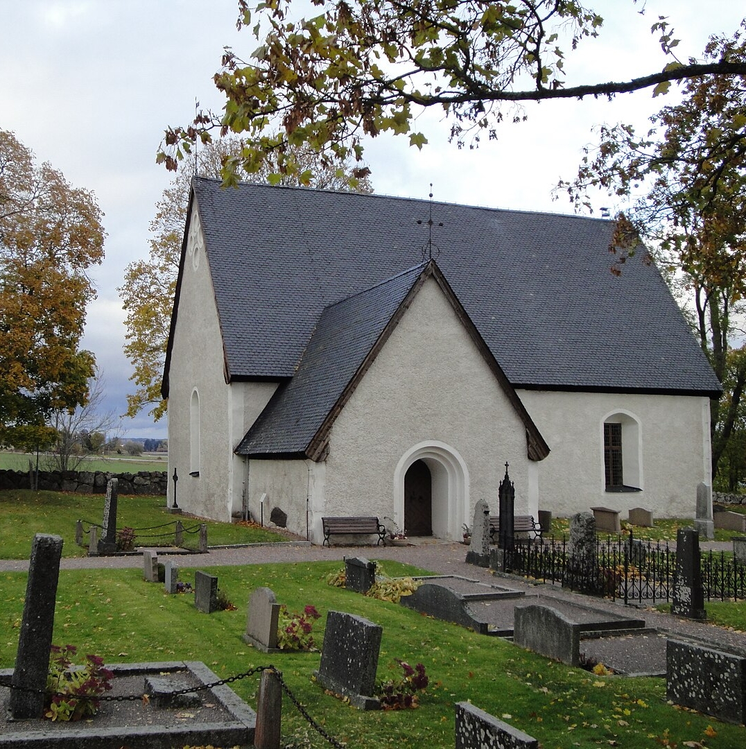 Foto av Lunda kyrka. I förgrunden syns flera gravstenar och delar av kyrkogården.