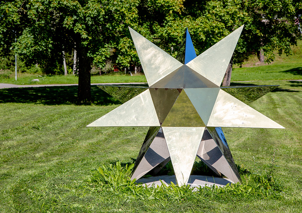 En skulptur av en guldglänsande stjärna på en gräsmatta.