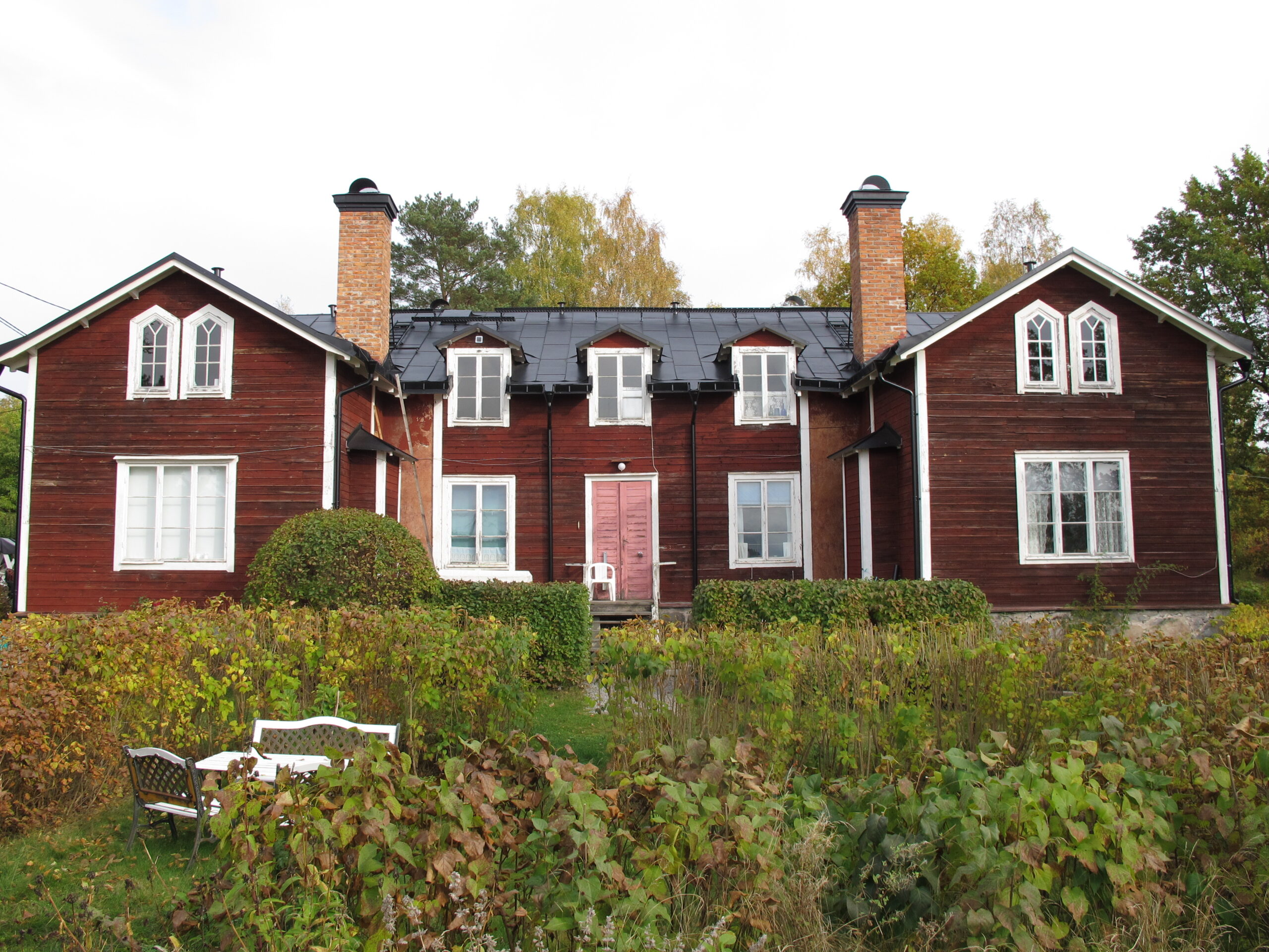 En röd tvåvåningsbyggnad med två höga skorstenar.