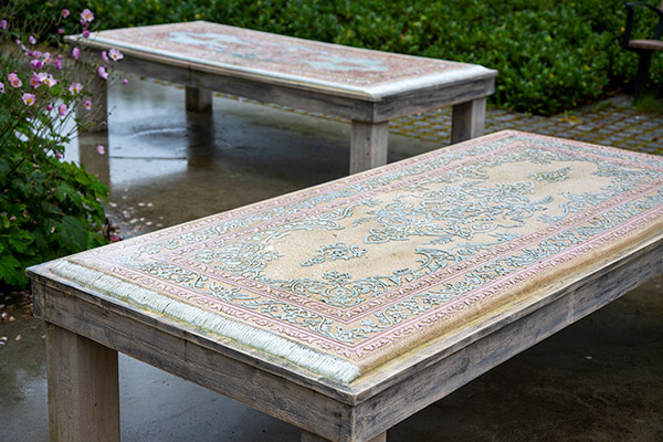 Två stenbord som ser ut som persiska mattor i en park.
