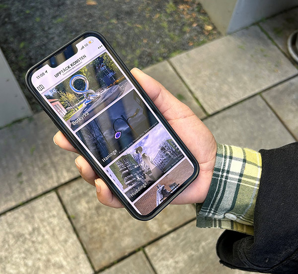 En hand håller i en mobiltelefon som visar appen Upptäck konsten.