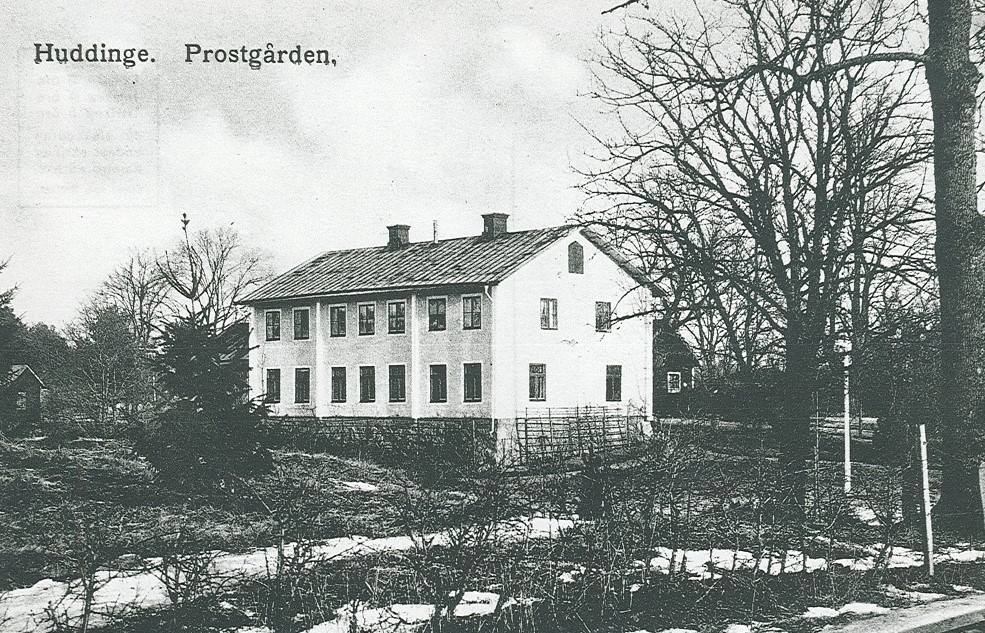 Ett svartvitt foto av en ljus tvåvåningsbyggnad .