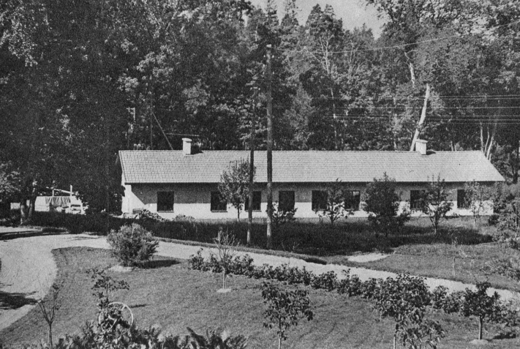 En fabriksbyggnad i ett plan omgiven av en park.