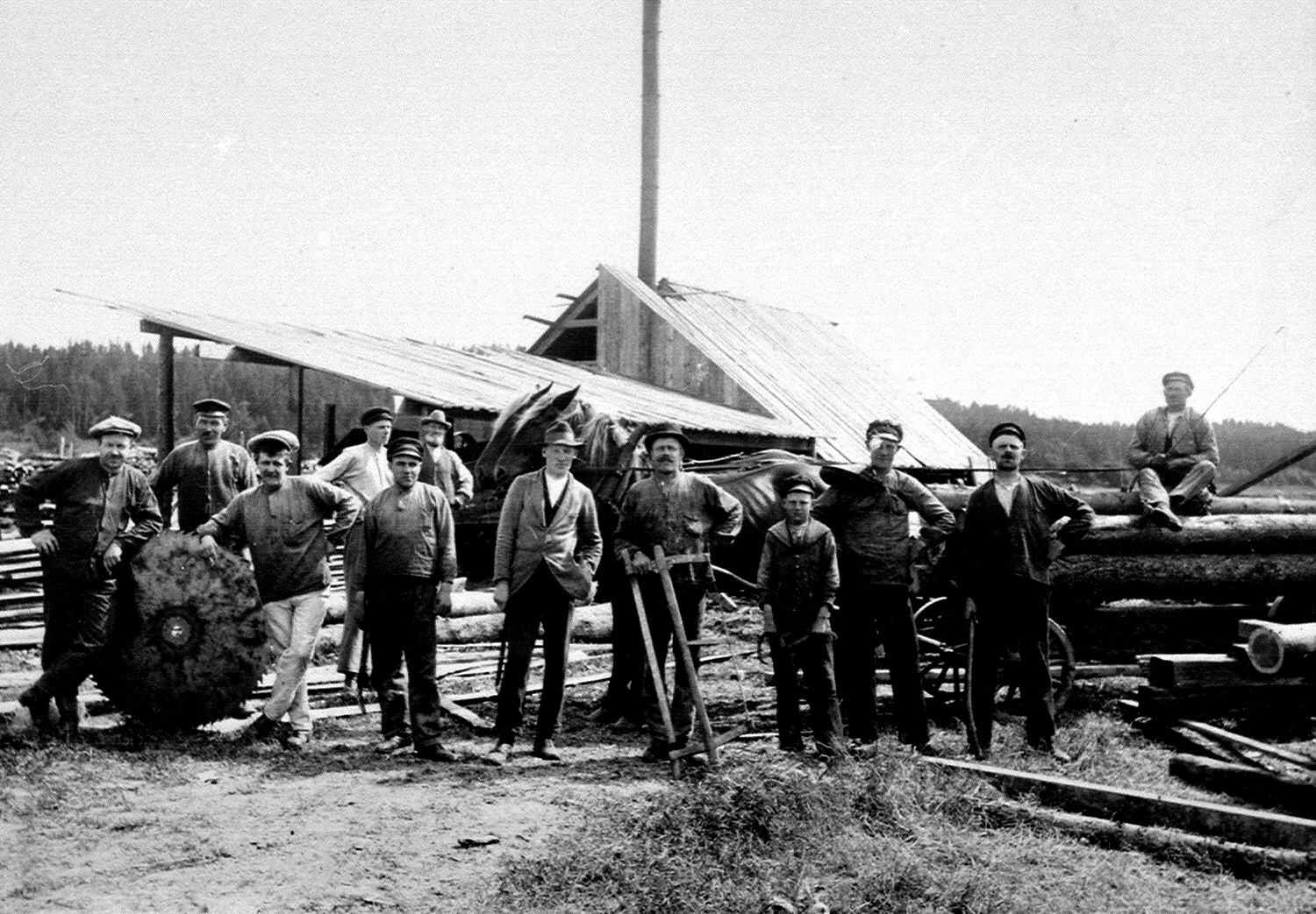 Tolv män poserar står uppställda med sågklinga, ramsåg och häst på ett svartvitt foto.