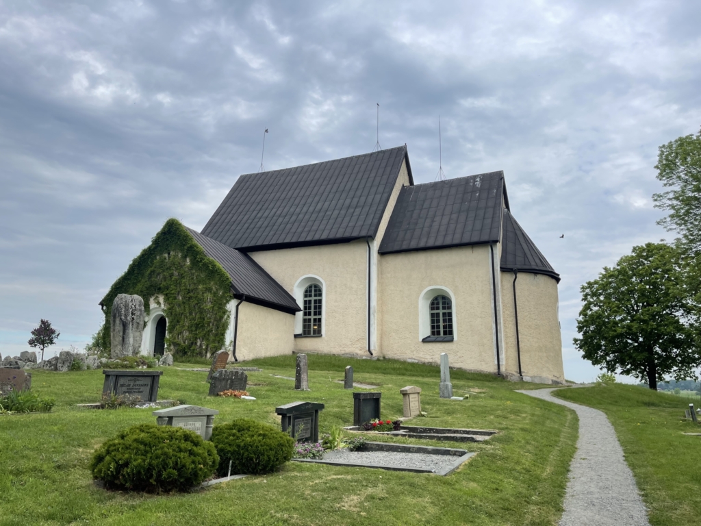 Vy av Markims kyrka, sett från framsidan. I förgrunden syns buskar och gravar.