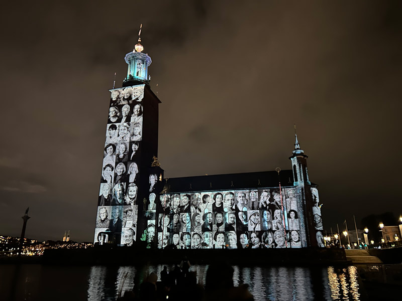 Stadshuset med ljusinstallation med porträtt av kvinnor i grått och blått.