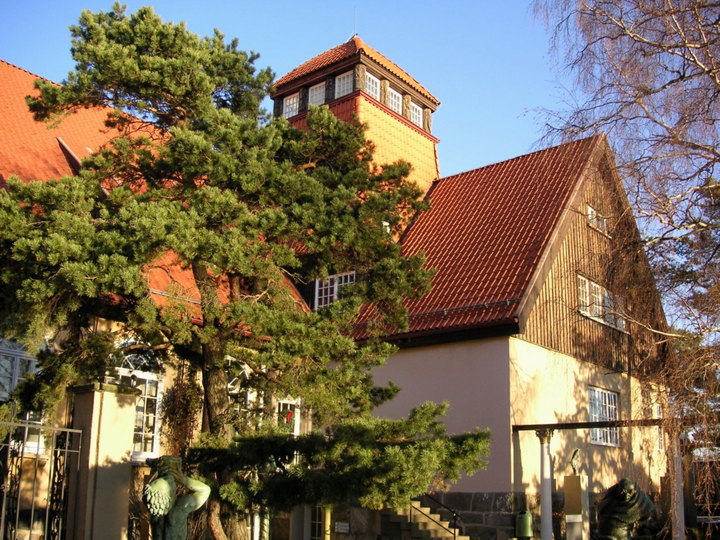 Baksidan av en sekelskiftesvilla. Framför villan står ett barrträd.