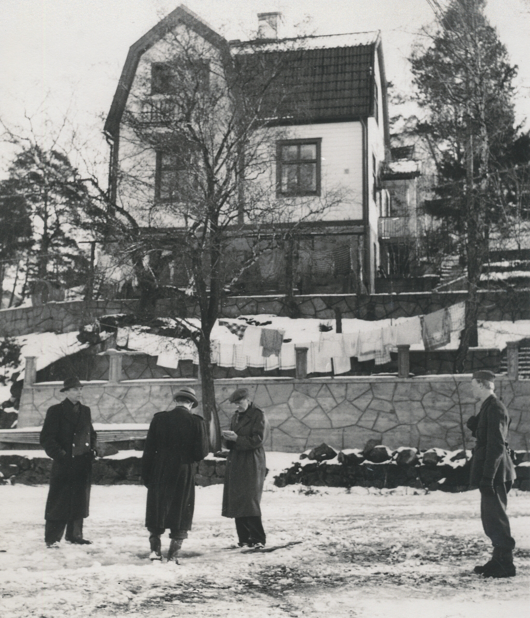 Fyra män står framför en högt belägen villa.