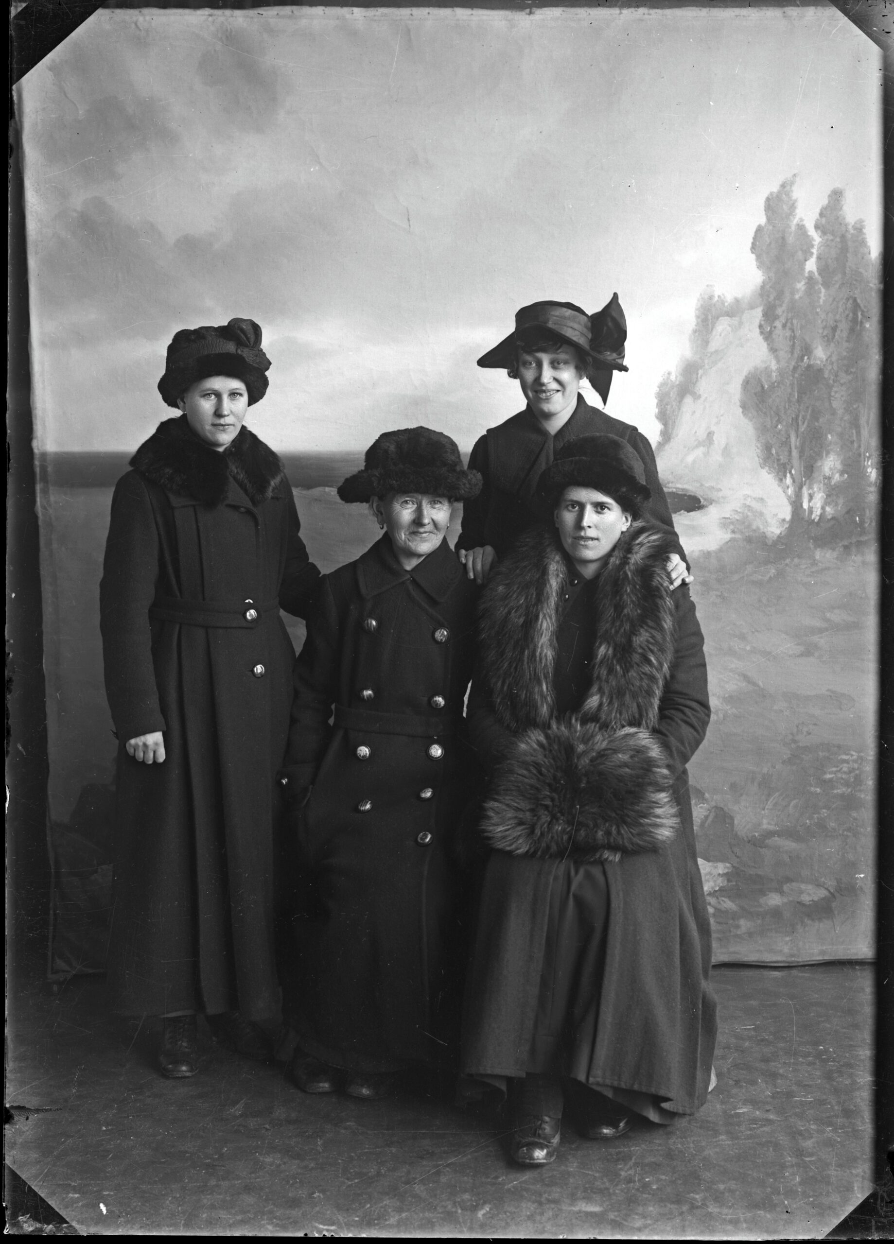 Fyra kvinnor klädda i ytterkläder och hattar.