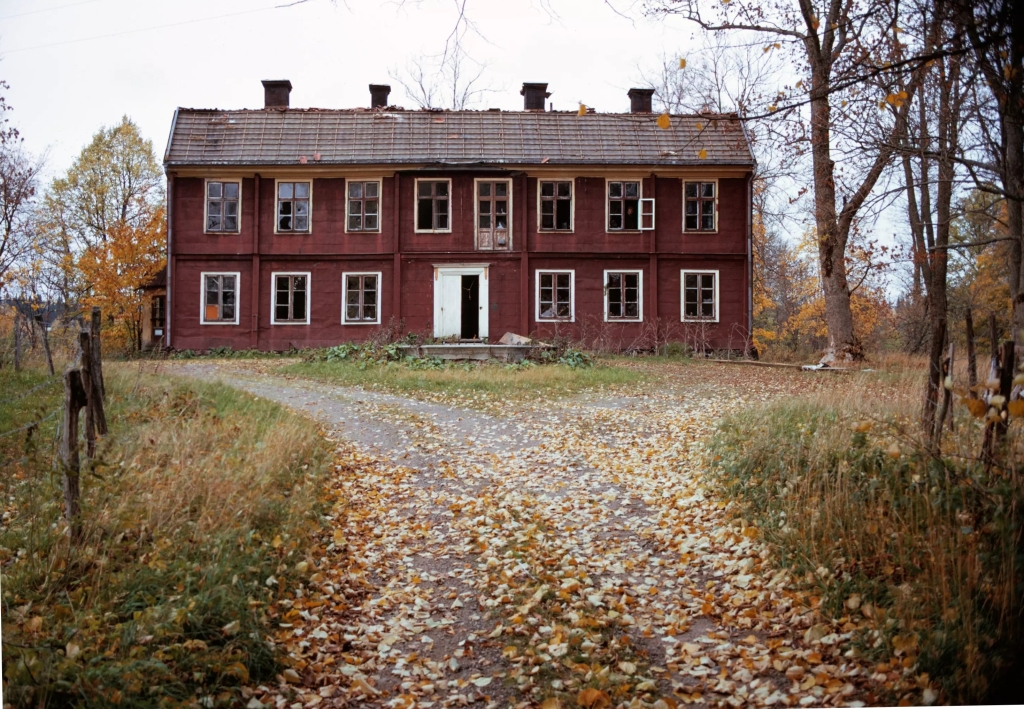 En förfallen herrgård i trä. Rödmålad.