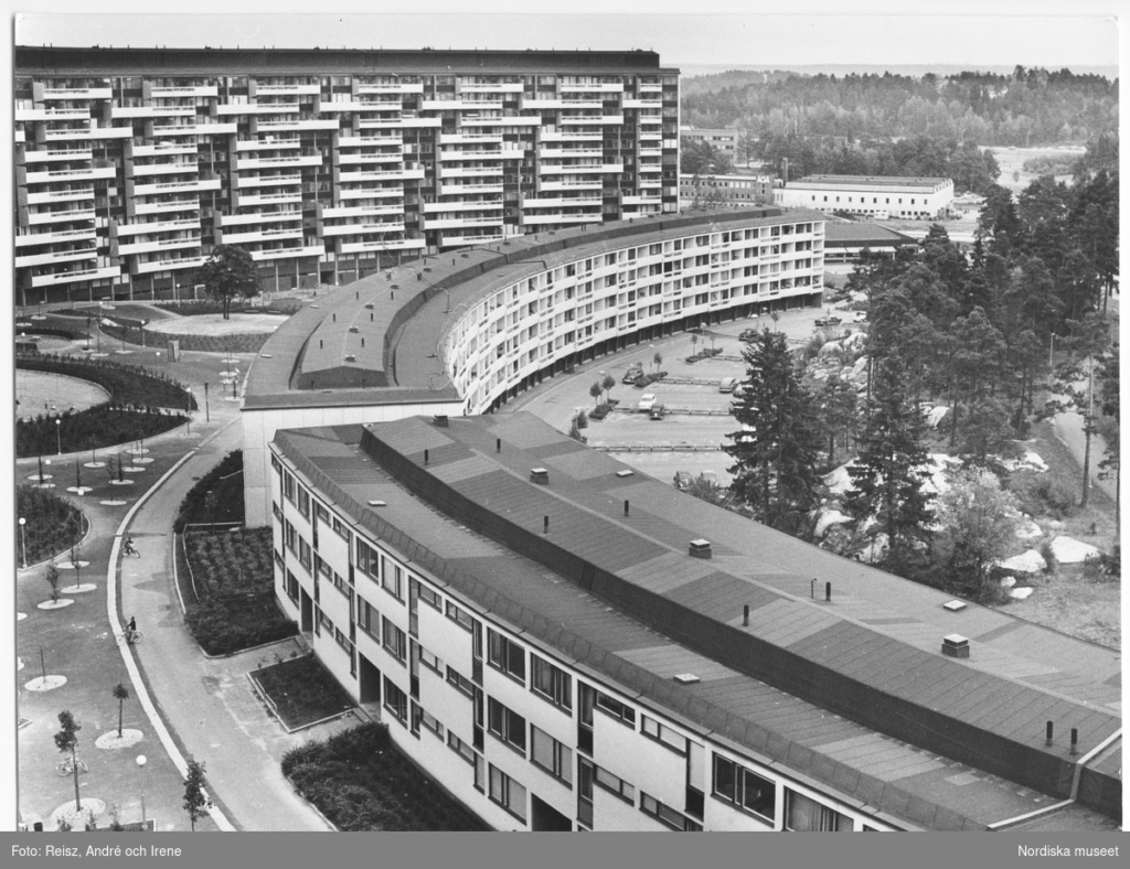 Svartvitt foto. Lägenhetshus i böjd form.