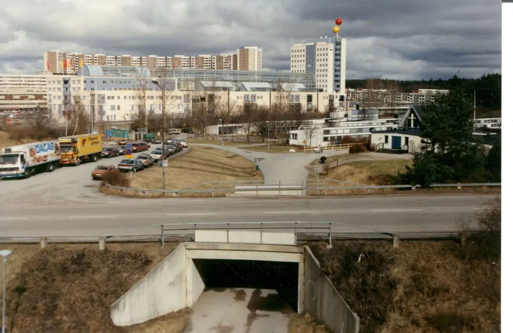 Fotografi. Bilväg, tunnel, parkering och centrumbebyggelse.