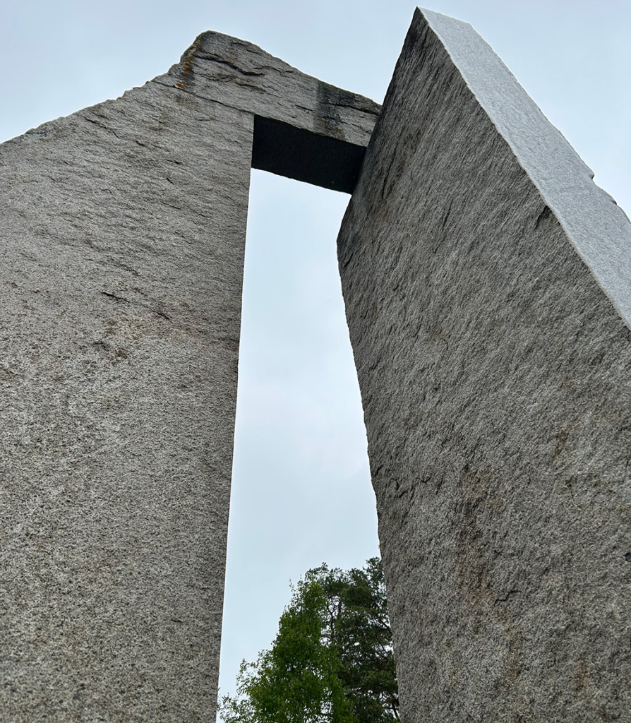 Två gråa stenar som sitter i hop. Mot en grå himmel.