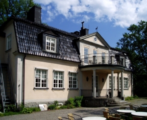 En mindre herrgårdsbyggnad med svart tak.