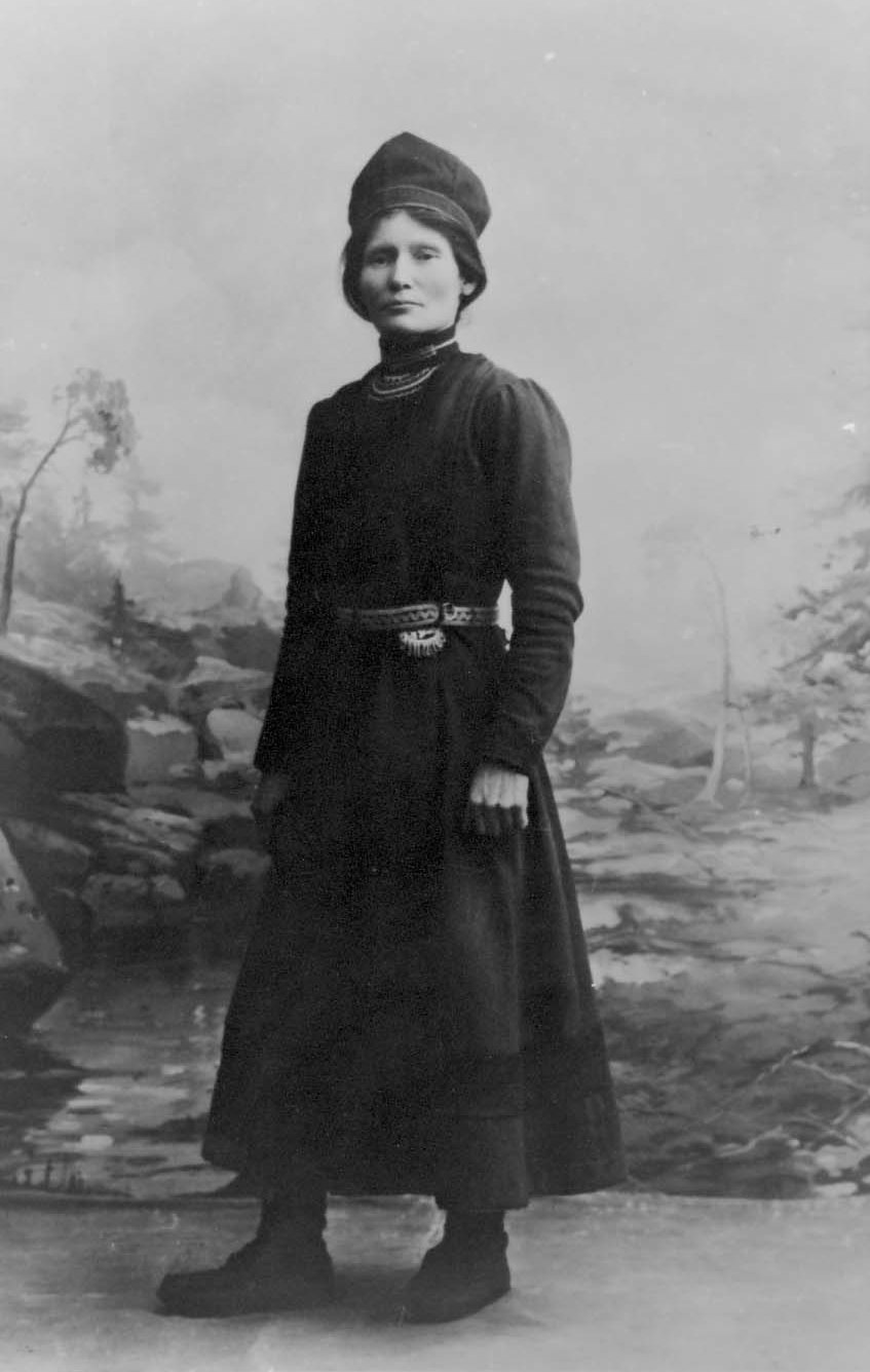 Svartvitt foto av kvinna. Hon bär en samisk klänning och huvudbonad.