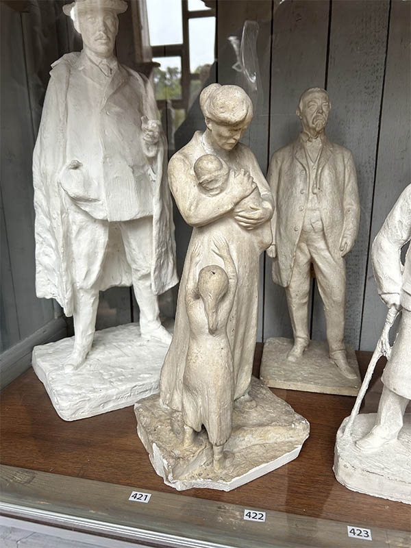 Flera små skulpturer. I fokus en kvinna som håller ett litet barn med en större flicka framför