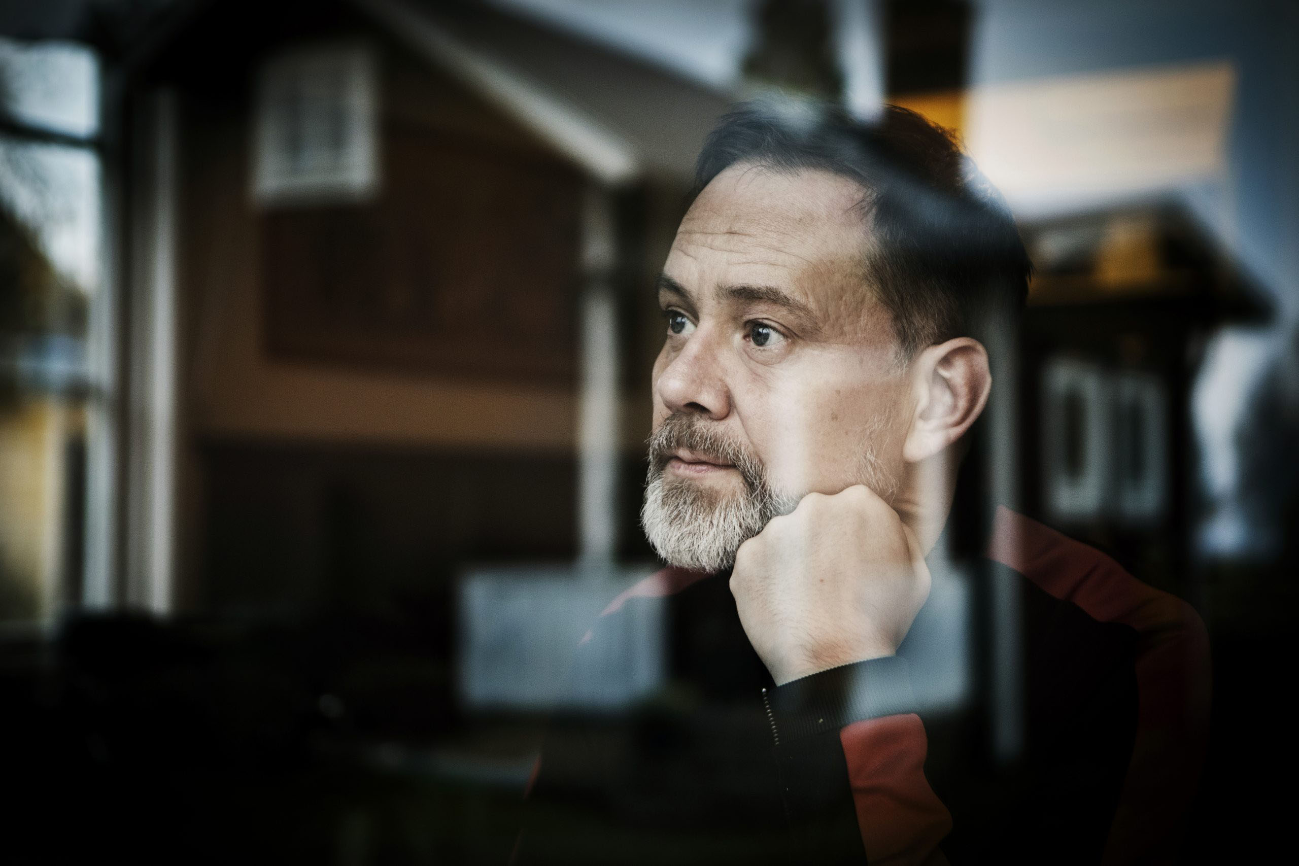 Man med skägg som sitter med som sitter med handen mot kinden.