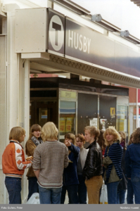 Tunnebaneskylten över ingången i bildens överkant. Ungdomarna i en tät grupp under.