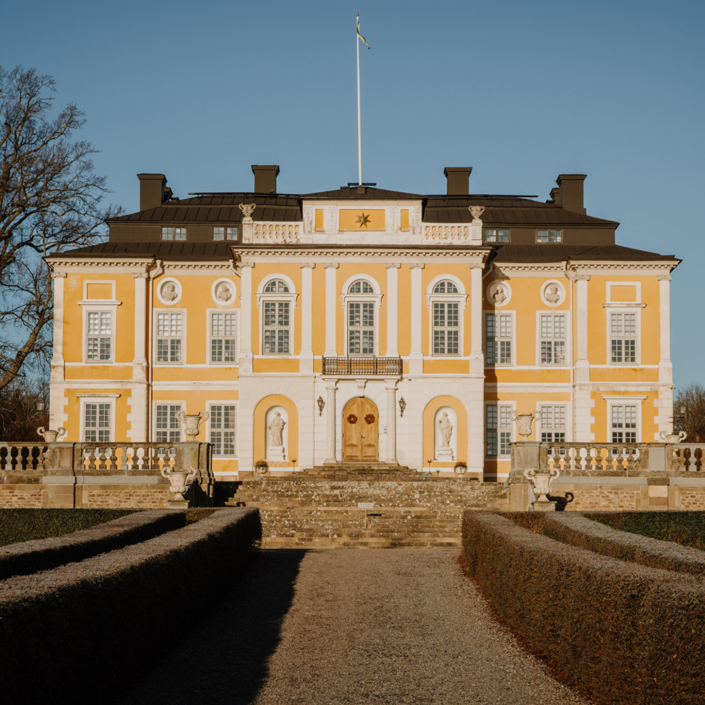 Gult barock-slott med höga fönster.