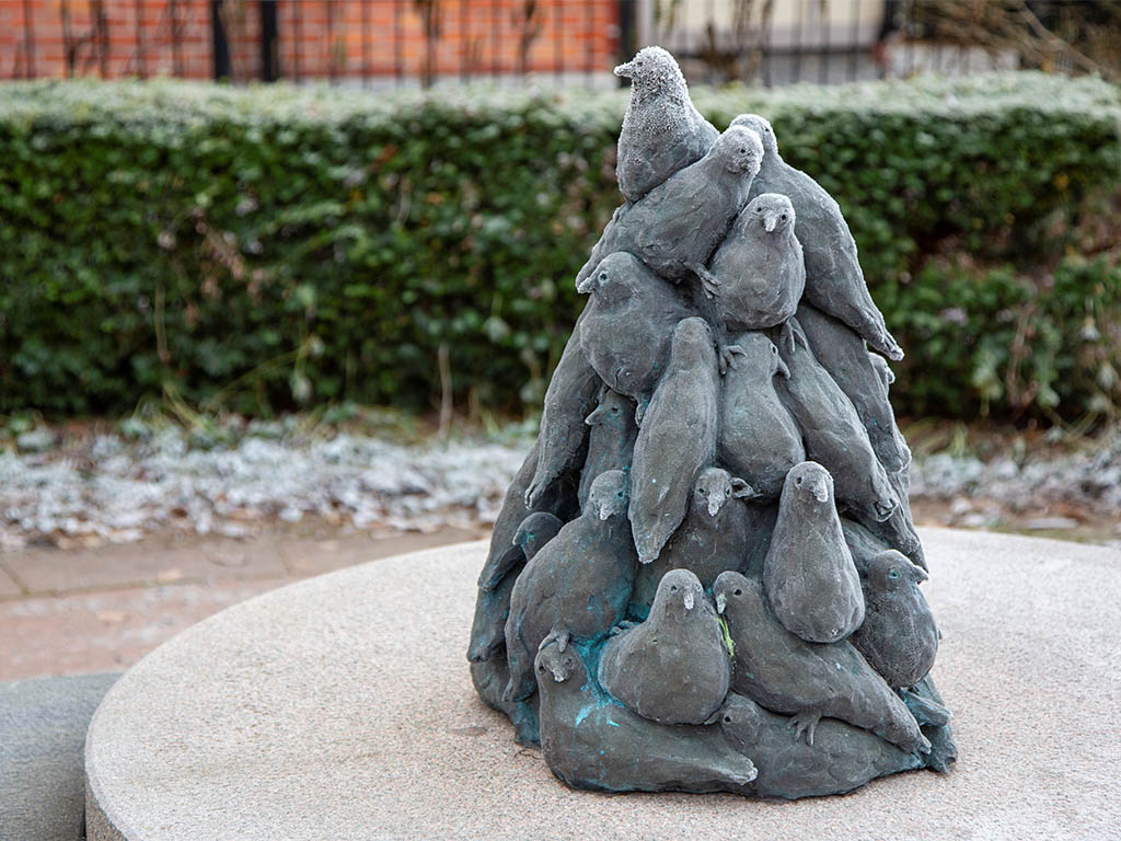 Skulptur av ett berg med duvor på en rund sockel.